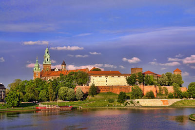 Buildings at waterfront against cloudy sky