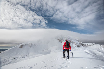 Rear view of woman on snowcapped mountain against sky