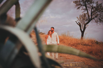 Young couple standing on steps seen through plant