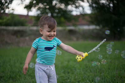 Cute boy playing with bubble wand on field