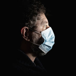 Portrait of an adult male person wearing a surgical mask for protection from the coronavirus.