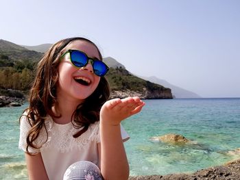 Young woman wearing sunglasses on beach against sky