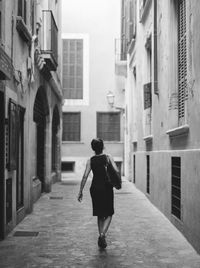 Rear view of woman walking on street amidst buildings