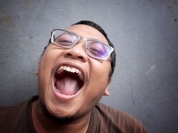 Portrait of happy man wearing sunglasses against wall