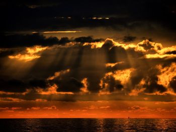 Scenic view of sea against dramatic sky during sunset