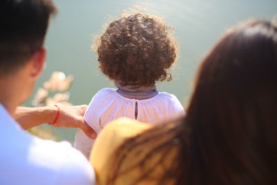 Rear view of father and mother with daughter at lakeshore