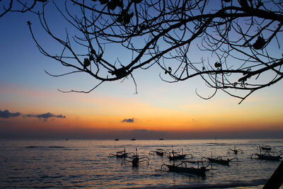 Silhouette bare tree by sea against sky during sunset