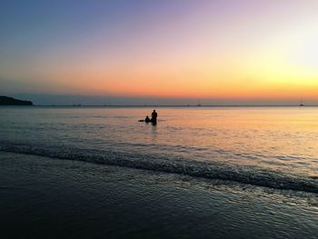 Silhouette people on beach at sunset