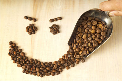 Cropped hand of person spilling coffee beans on table