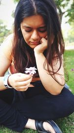 Young woman looking down while sitting outdoors
