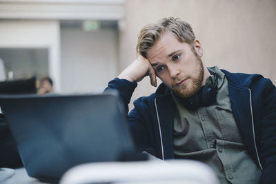 Tired computer programmer using laptop in office