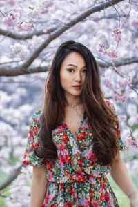 Portrait of young woman standing against trees