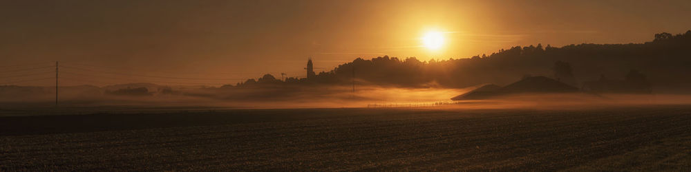 Scenic view of silhouette field against sky during foggy weather