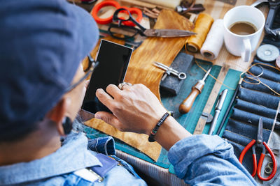 High angle view of tailor using smart phone at workshop