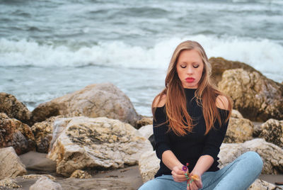 Young woman sitting on rock at beach