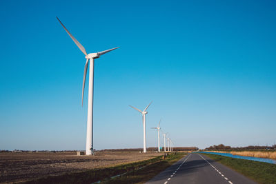 Wind turbines on field against clear blue sky