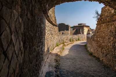 Alley amidst old wall against sky