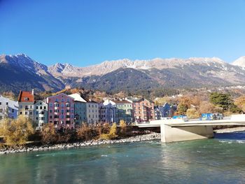 Scenic view of sea by buildings against clear blue sky