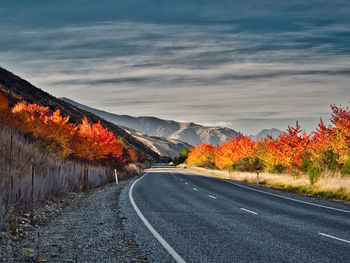 Road amidst trees against sky during autumn