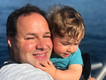 Portrait of smiling man with son against sea