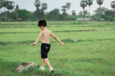 Full length of shirtless man standing on field