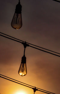 Low angle view of illuminated light bulb against sky at sunset