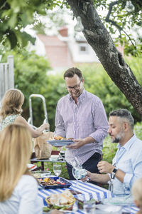 Mature friends enjoying and sharing food at table in weekend party