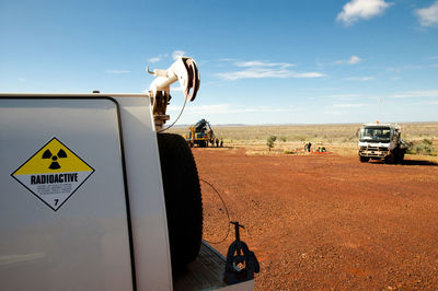 Close-up of commercial land vehicles on field against sky