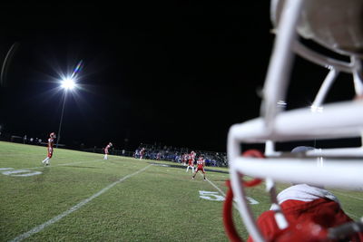 People playing soccer on field at night