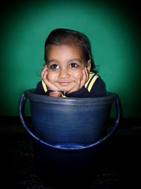 Close-up of cute girl sitting in bucket at home