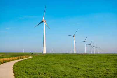 Windmills on field against blue sky