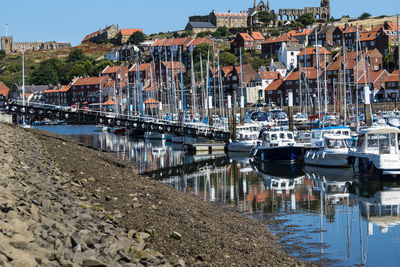 Boats moored at harbor against sky