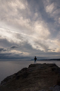 Full length of boy standing on cliff against sea