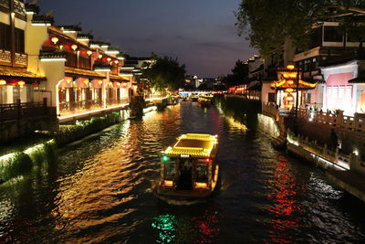 Boats moored on canal in city at night