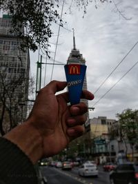 Midsection of man holding umbrella against sky in city