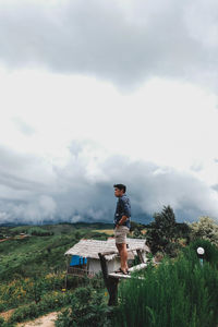 Man sitting on field against sky