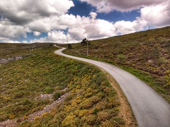 Scenic view of road amidst field against sky