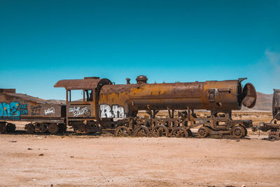 Old abandoned train on field against sky