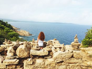 Rear view of girl standing amidst stone stacks looking at sea