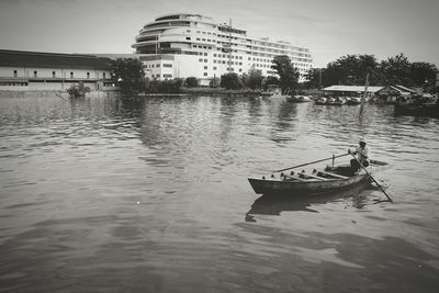 Boat in river against buildings in city