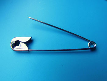 High angle view of safety pin over blue background