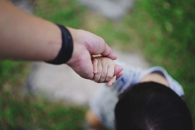 Midsection of couple holding hands against blurred background