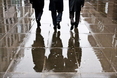 Low section of people walking on wet puddle