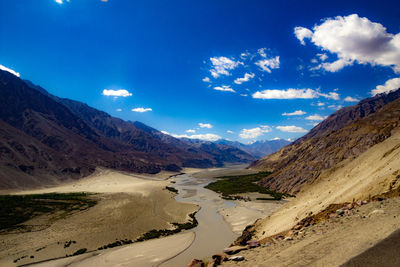 Scenic view of landscape and mountains against blue sky