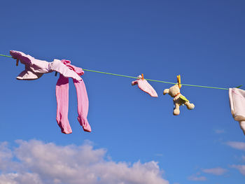 Low angle view of clothespins hanging on rope against sky