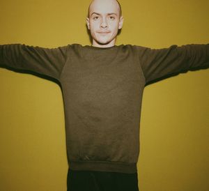 Portrait of man with arms outstretched standing against yellow background