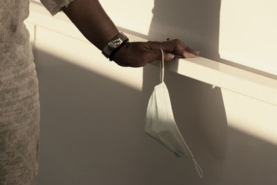 Midsection of man holding umbrella against wall