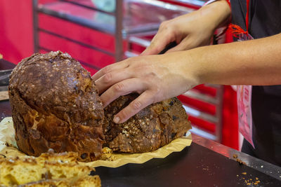 Typical italian sweet panettone cut by woman's hands