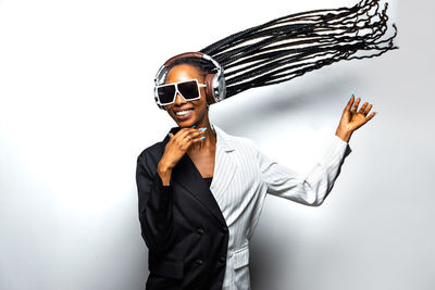 Portrait of young woman wearing sunglasses against white background