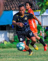 Full length of man playing with ball on soccer field